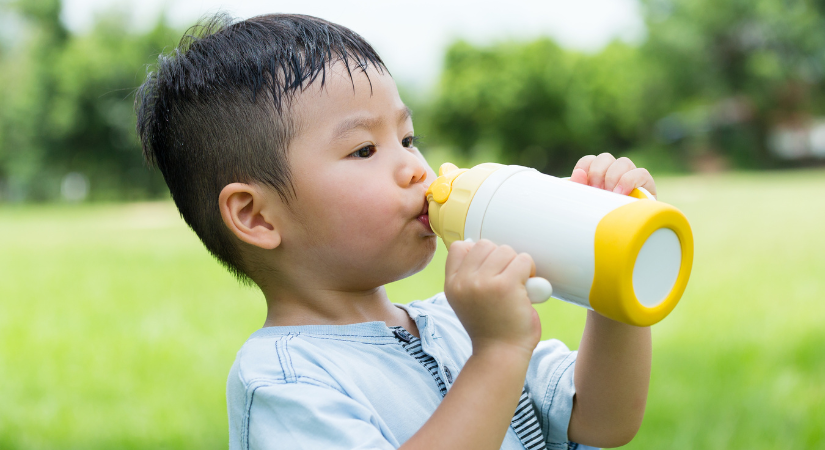 A young child keeping hydrated during hot weather at nursery.