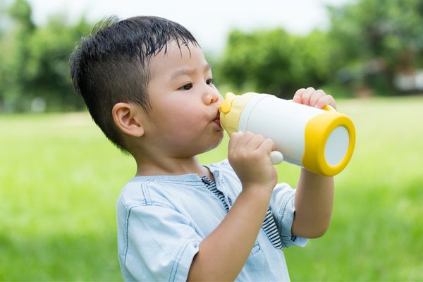 A young child keeping hydrated during hot weather at nursery.