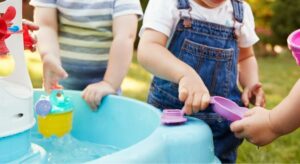 Children playing with water and measuring cups at nursery, introducing an STEM activity into their early learning