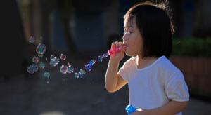 A young girl playing with soapy water as part of a water play activity at nursery.