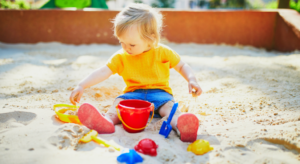 A small child playing in the sand as part of a Beach Play exercise at nursery.