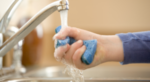 A child filling up a sponge with water as part of a water play activity called Sponge Toss.