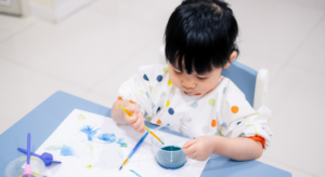 A young child making art with water and colours at a nursery, an engaging water play activity idea.